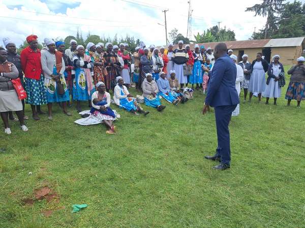 Long’ole speaks to a large group of women on a field