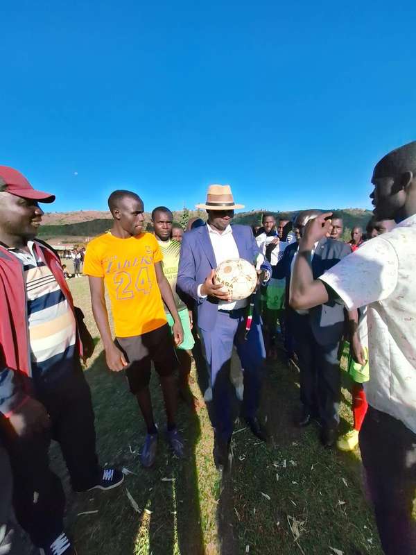 Long’ole in a suit and hat holding a football among young players